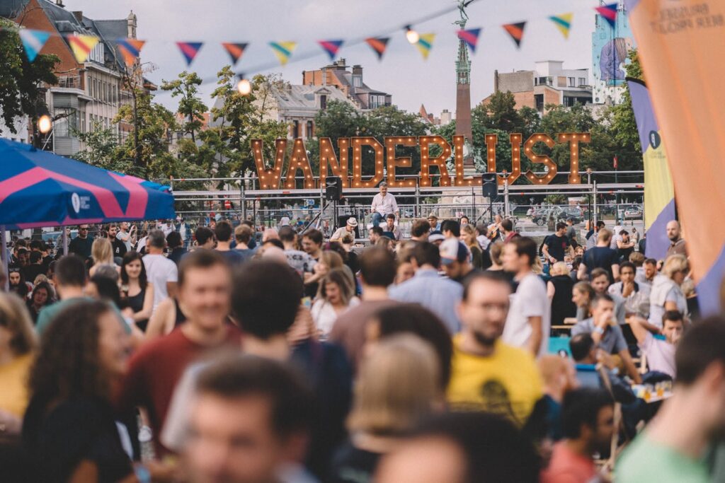 Giant WANDERLUST marquee letters over the festival crowd at dusk, Brussels